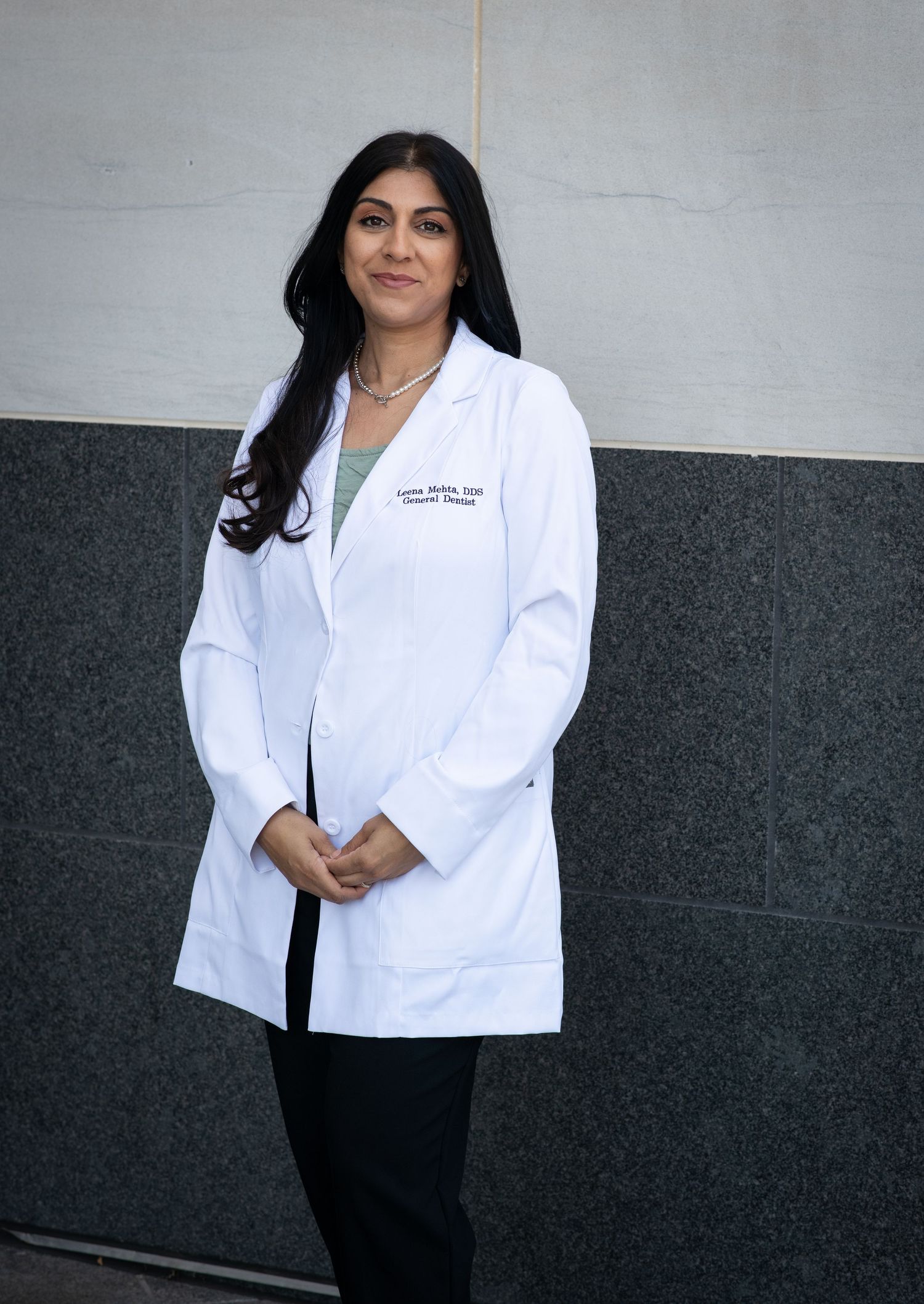 A healthcare professional in a white lab coat and black pants stands against a grey wall in various poses.