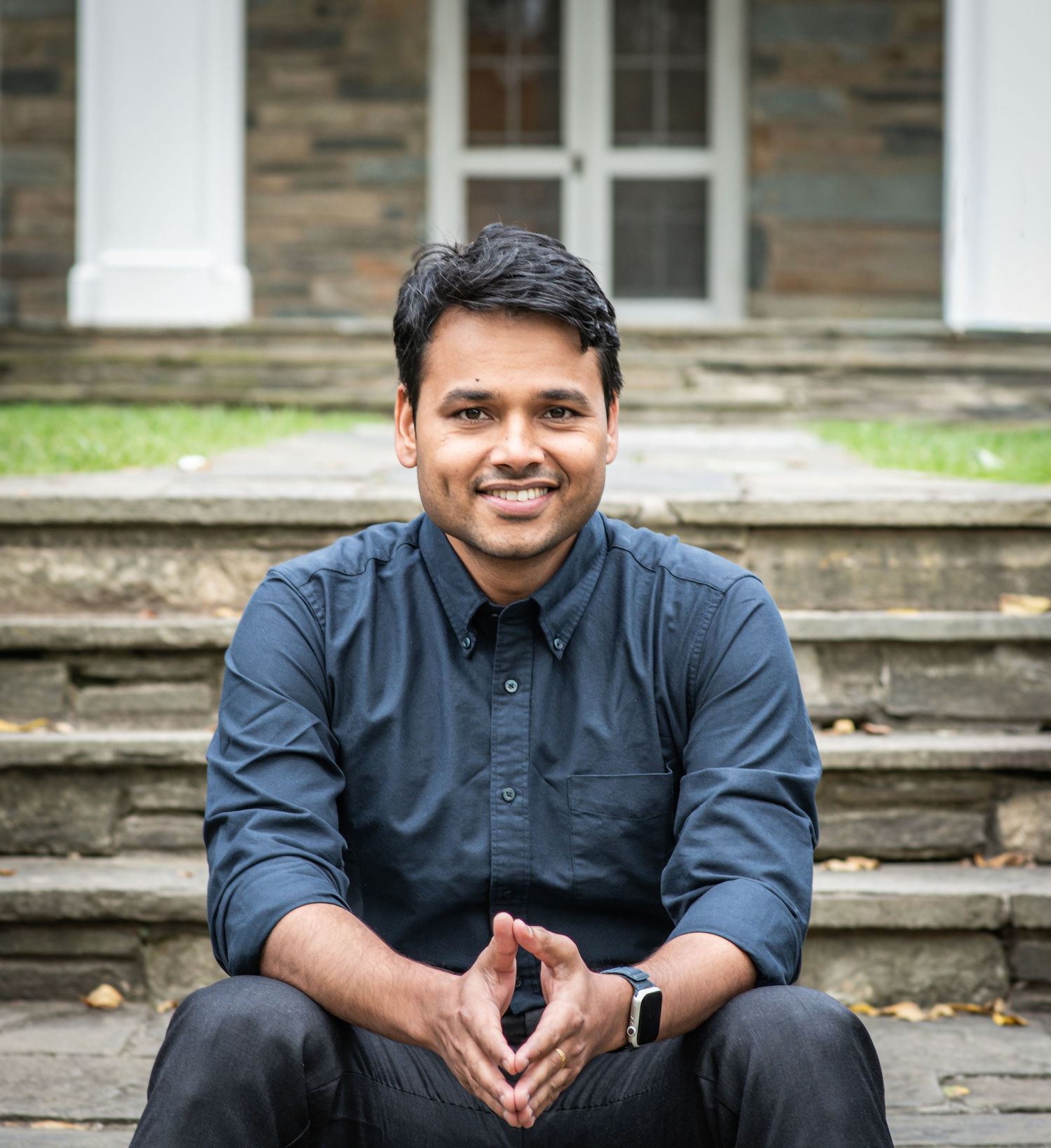 A person wearing a navy blue shirt sits casually on outdoor stone steps in a series of progressive poses.