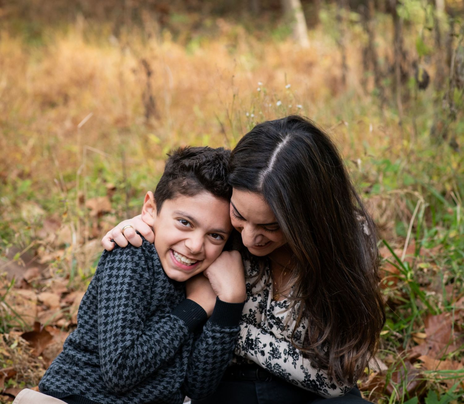 A tender moment captured between two people sitting together outdoors in an autumn setting.