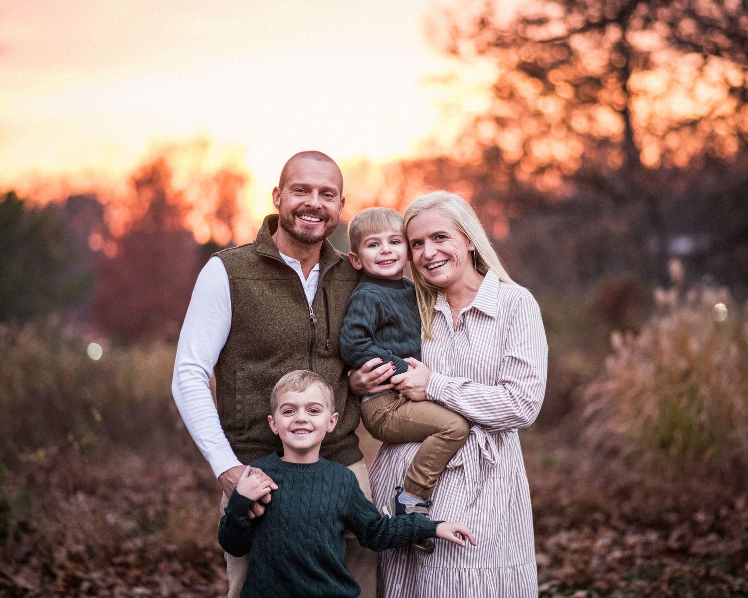 A group of people share joyful moments together during a golden sunset photo session in an autumn field.