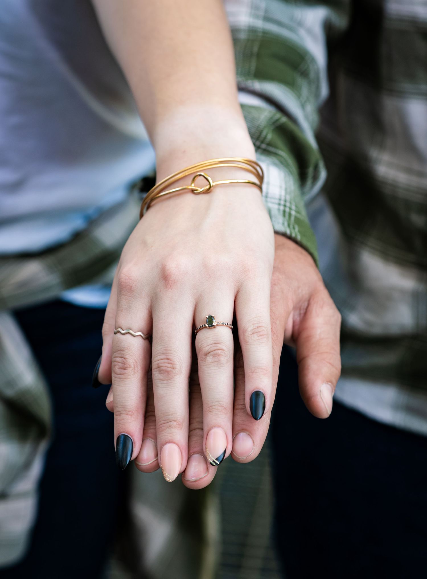 Close-up shots of hands wearing delicate rings and jewelry against casual clothing.