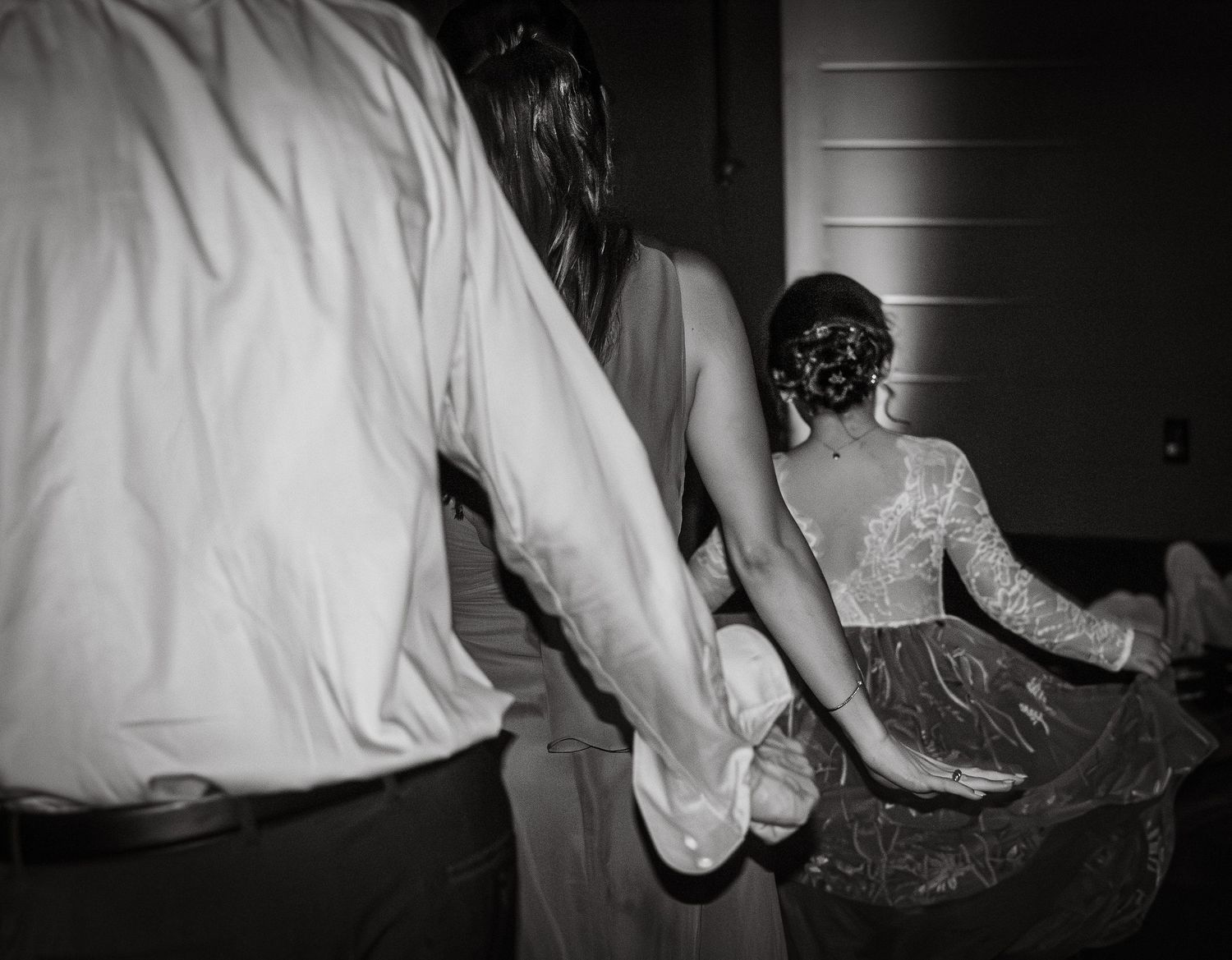 A series of black and white photographs showing wedding dress details and preparations in dim lighting.