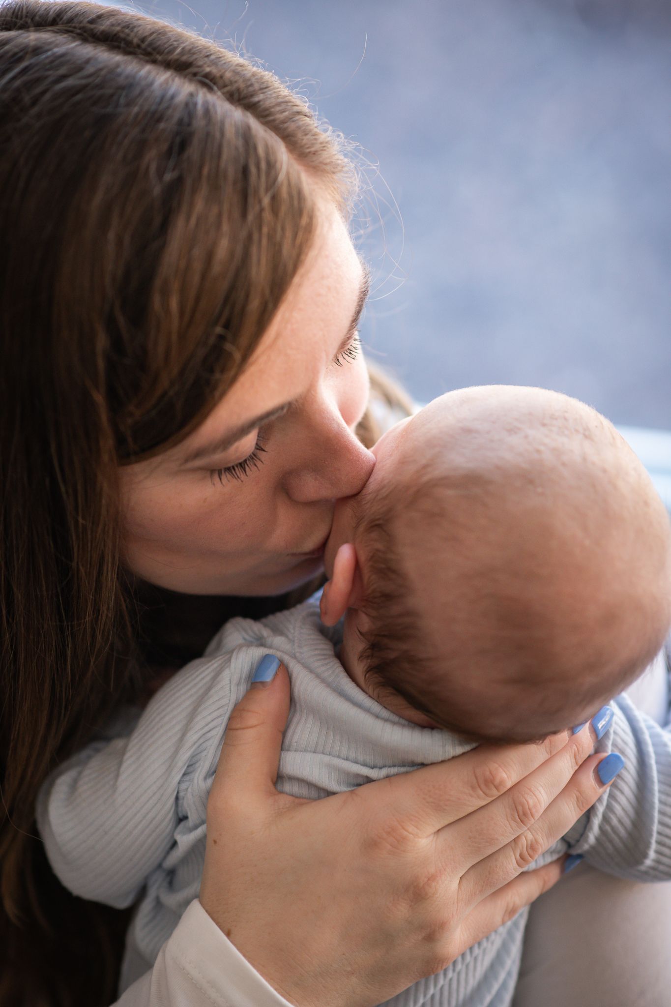 Tender sequence of a parent kissing their baby's cheek while holding them close.