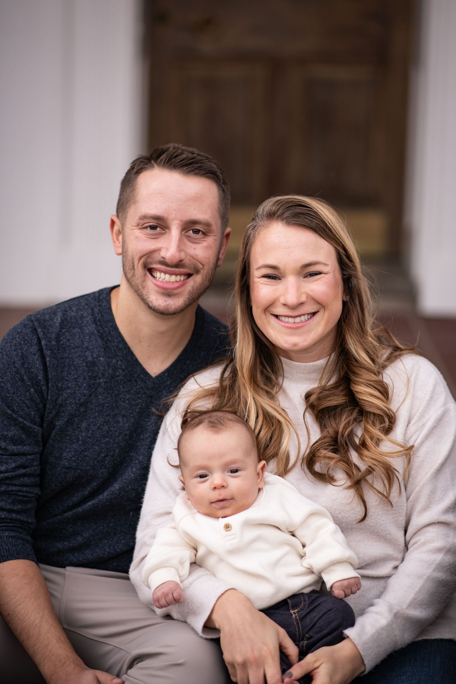 A family portrait series showing loving moments between parents and their young child in coordinated cream and navy outfits.