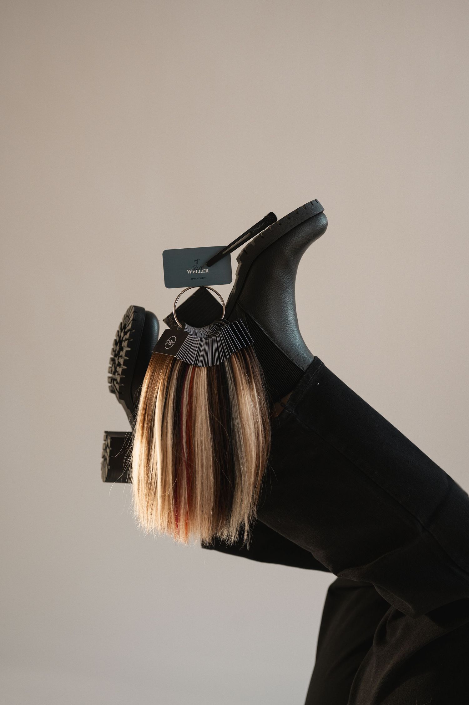 A black hair claw clip holding highlighted blonde and brown hair strands against a neutral background.