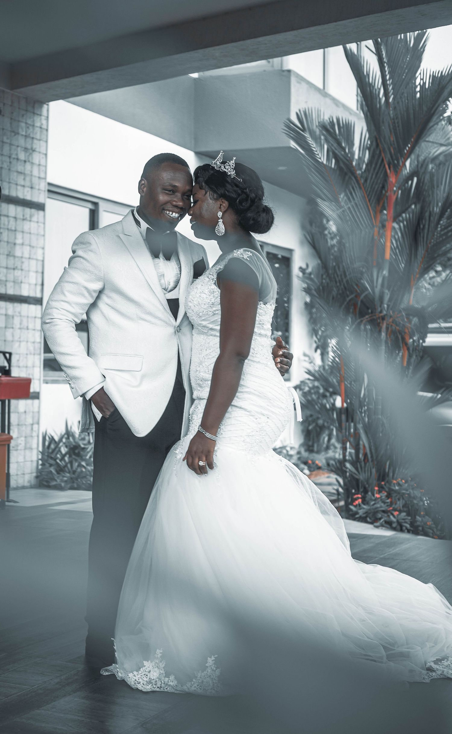 A romantic wedding couple shares an intimate dance moment in formal attire with dramatic lighting and foggy atmosphere.