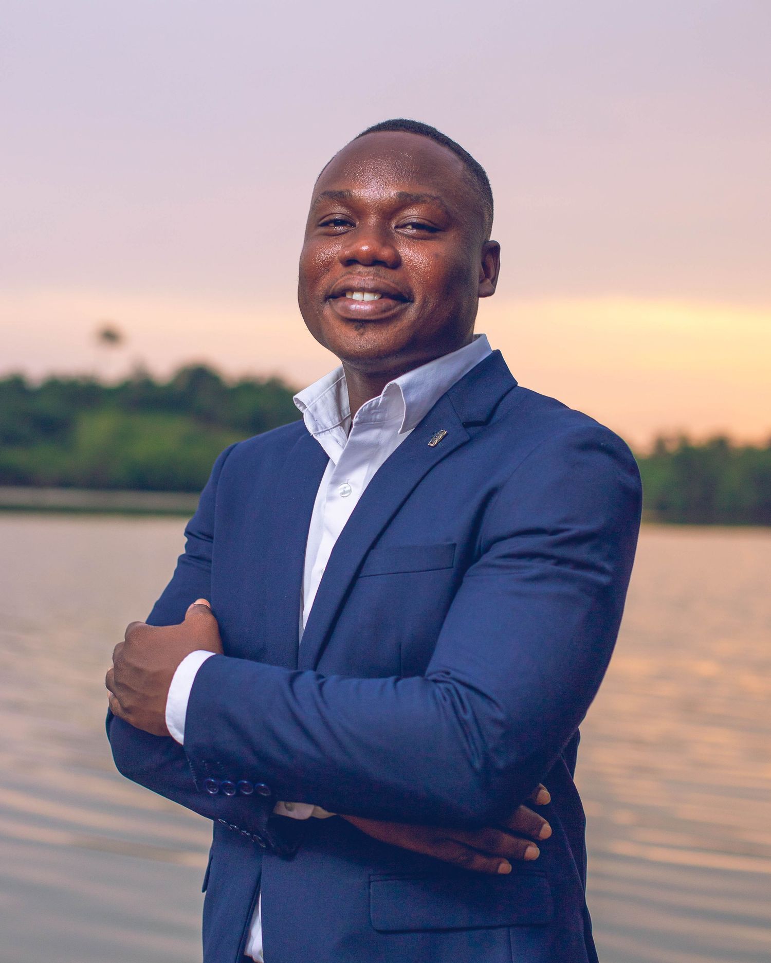 A businessman in a navy blue suit stands by a waterfront at sunset, shown in a series of poses.