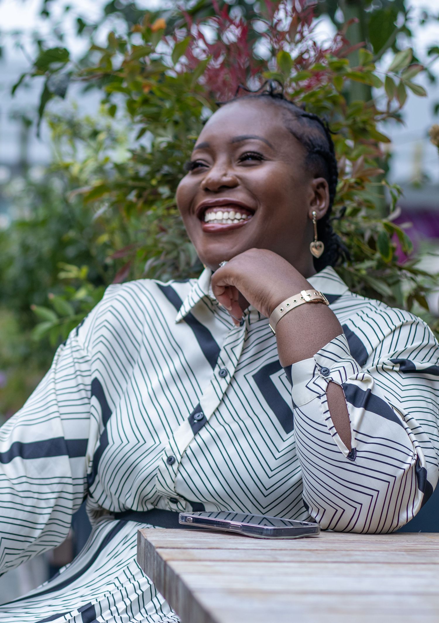 A candid portrait outdoors shows someone wearing a striped black and white patterned top while smiling warmly.