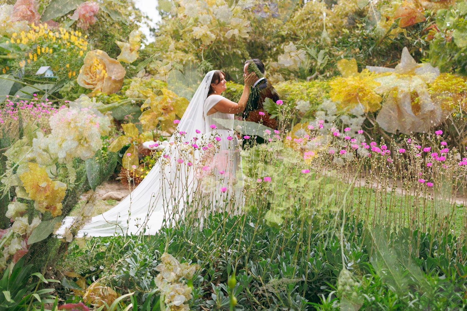 A dreamy double-exposure wedding portrait of a bride and groom surrounded by soft yellow and pink garden florals.