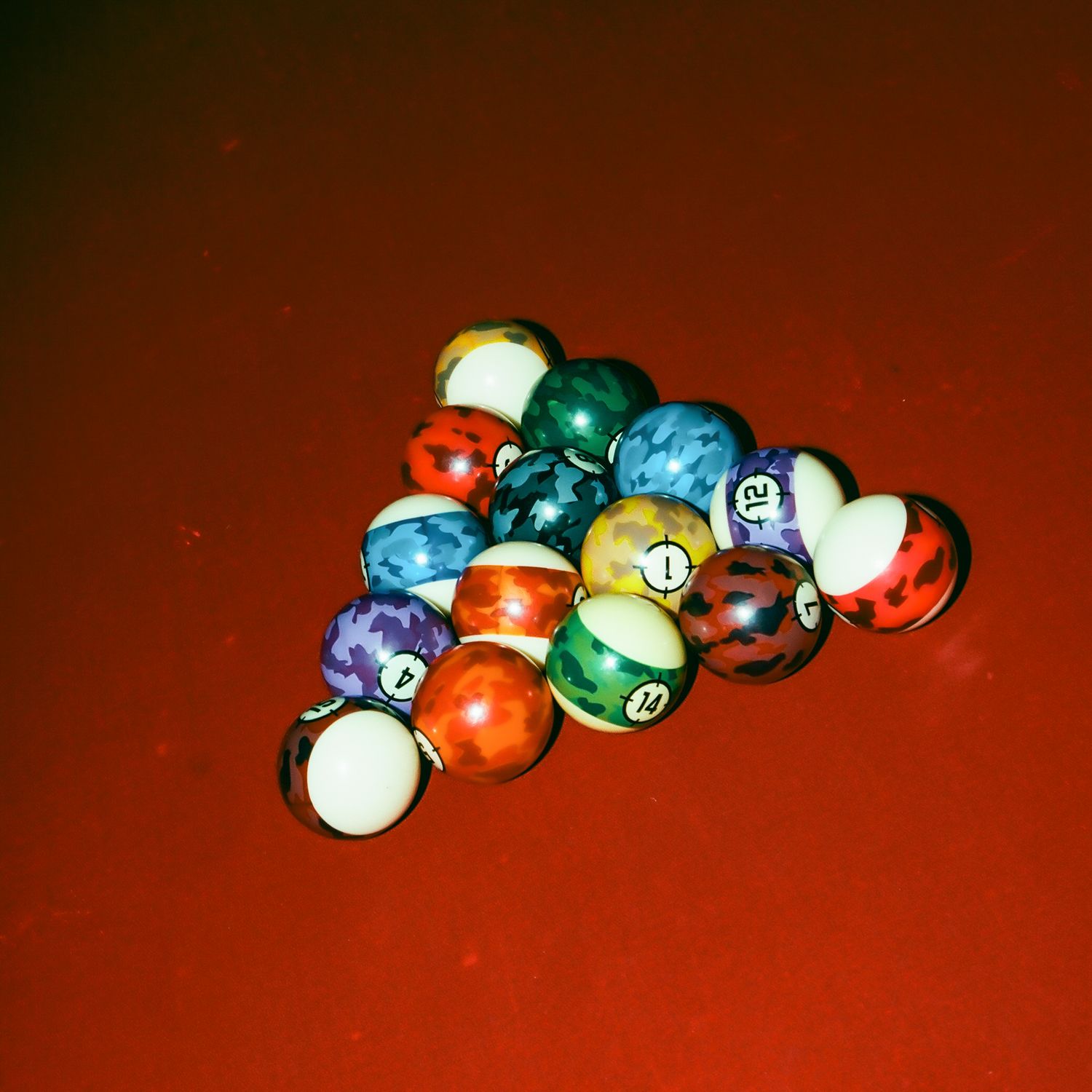 Colorful marbled billiard balls arranged in a triangle rack on a red pool table surface.