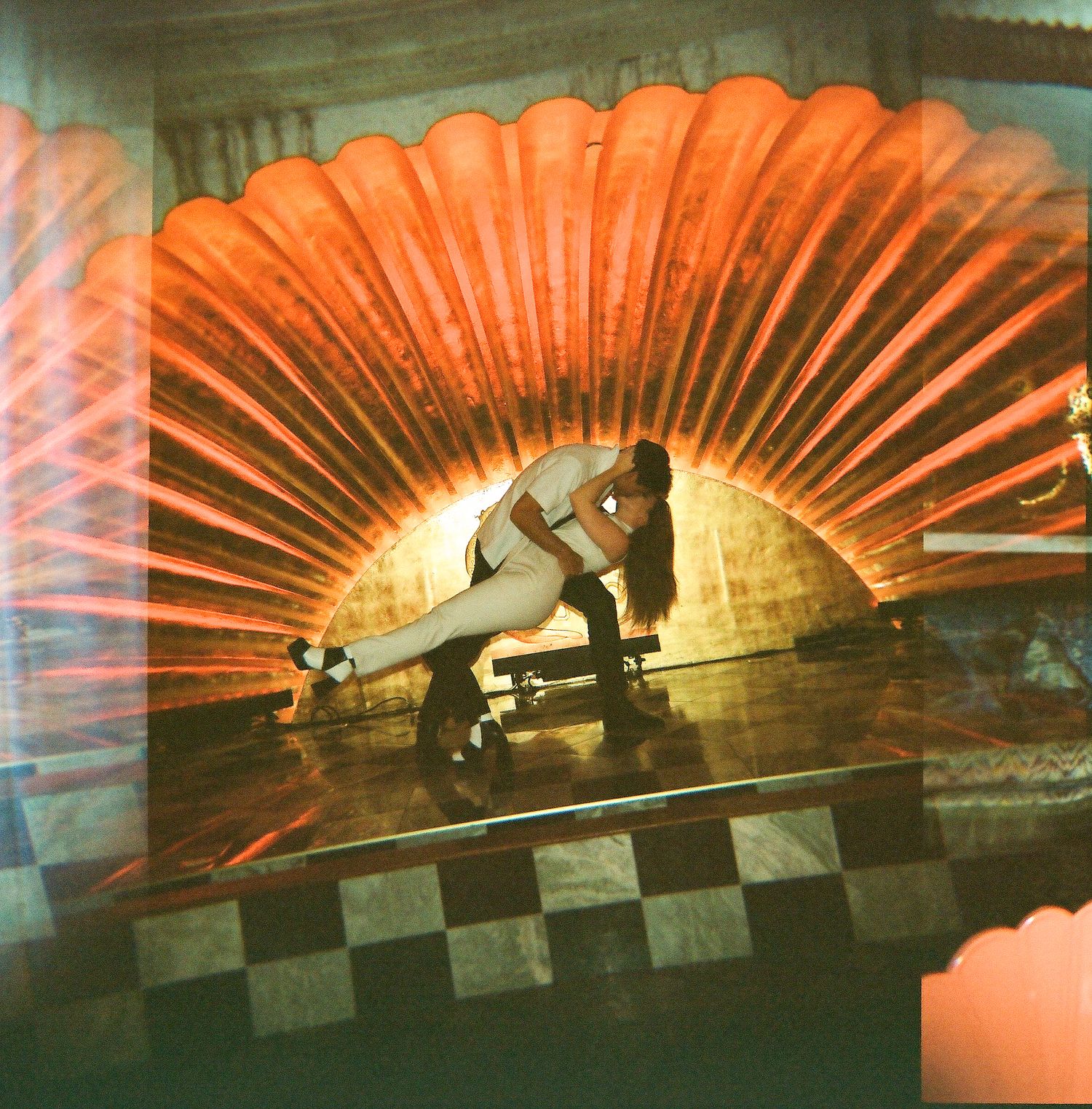 Person roller skating in front of a glowing red shell-shaped stage backdrop on a checkered floor.