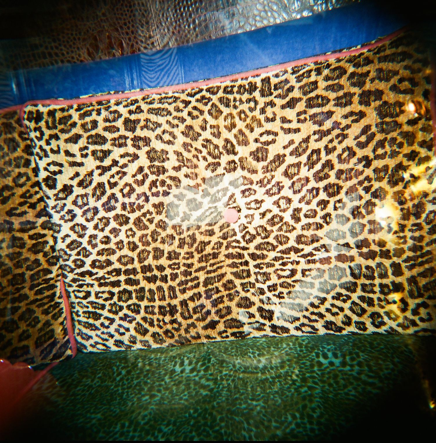 Close-up of a leopard print fabric surface with brown and black spotted pattern on a colorful background.