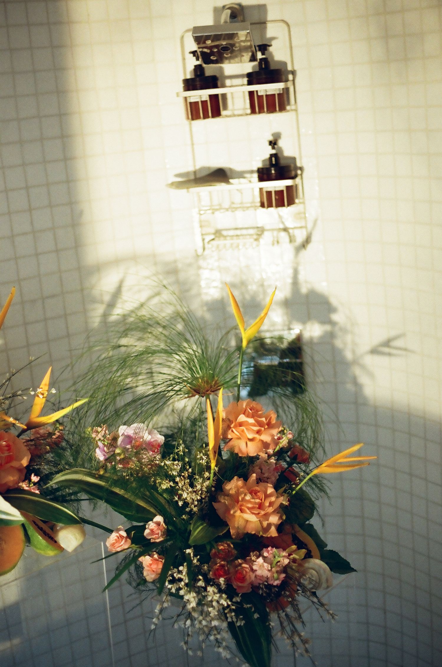 Tropical floral arrangement with birds of paradise and hydrangeas in a tiled shower setting.