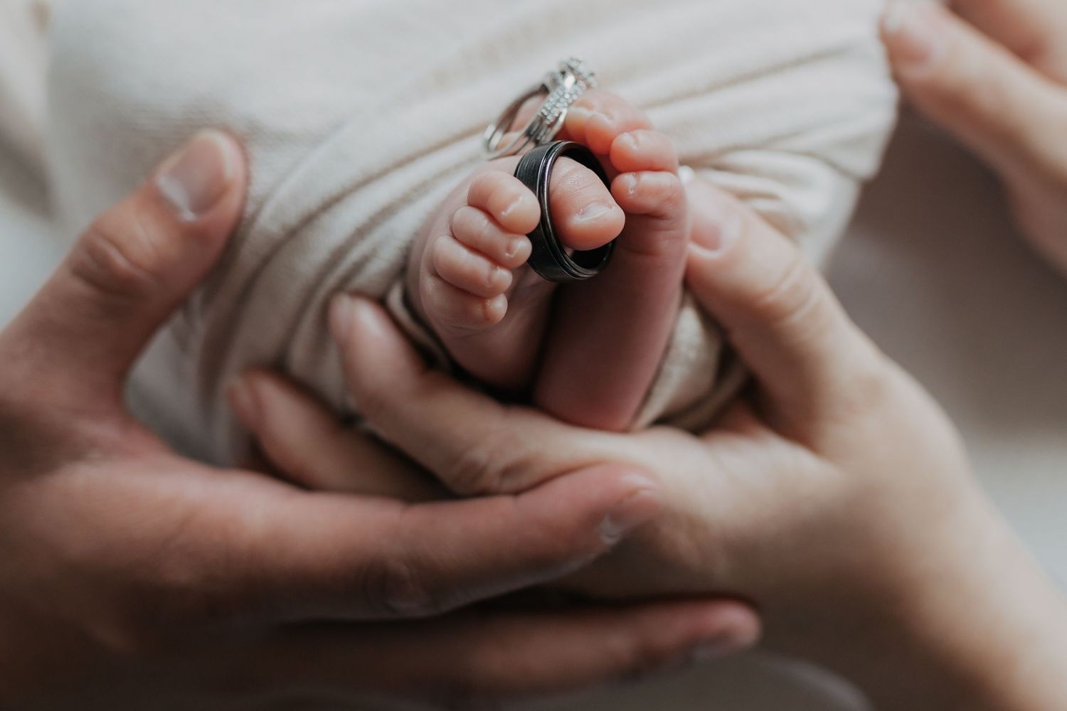 Close-up view of hands gently holding a baby's tiny foot during a tender care moment.