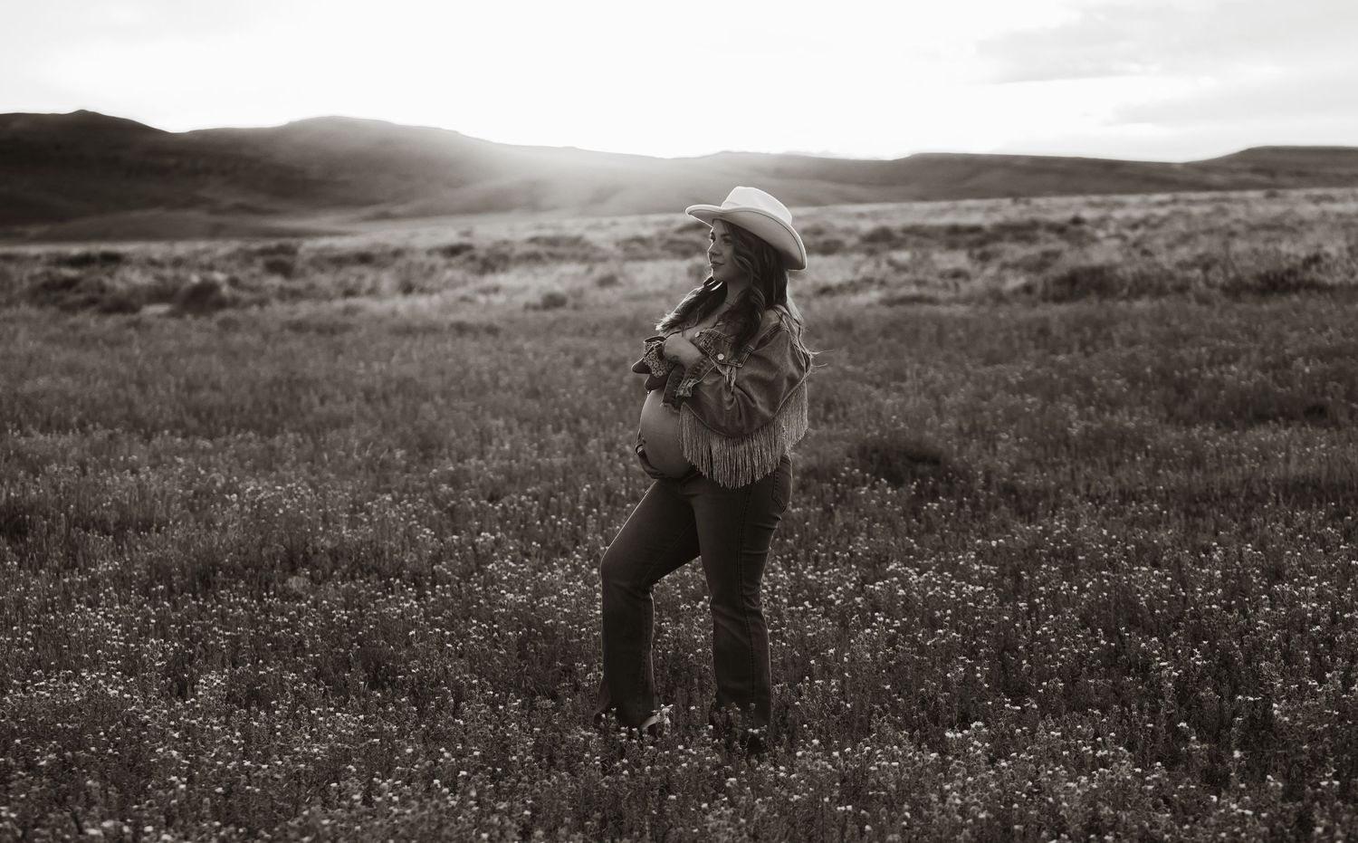 A maternity silhouette photo in black and white with rolling hills in the background.