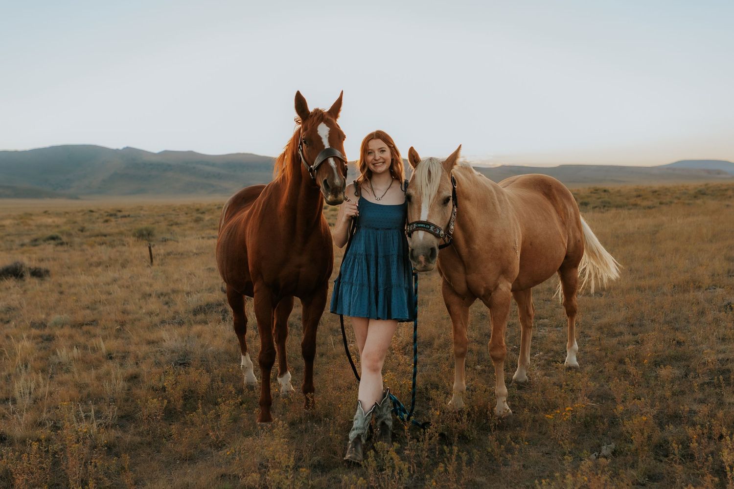 horses and riders stand together in a golden prairie field at sunset.