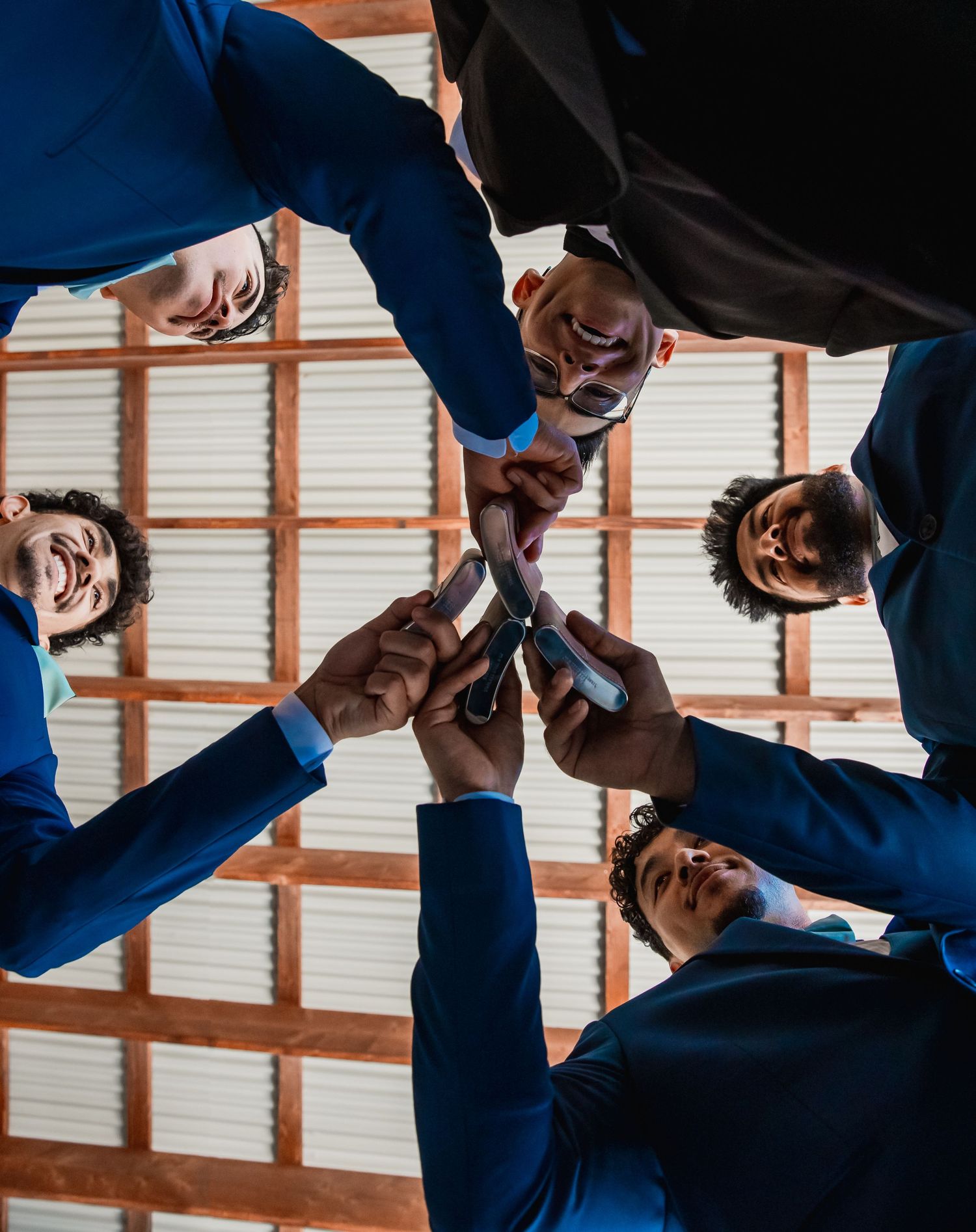 Business team huddling in a circle and looking down at camera in modern office setting.