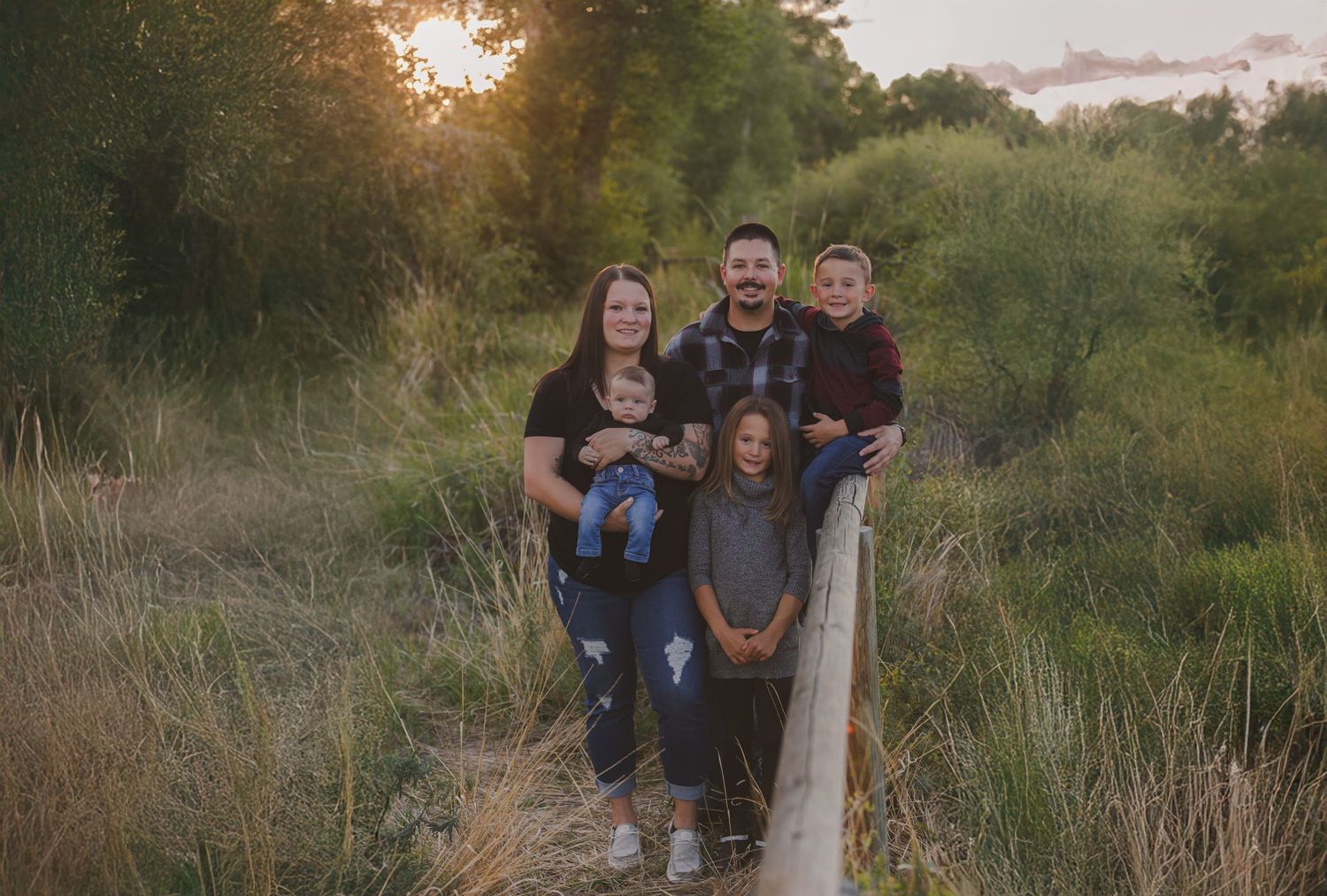 A family portrait on railroad tracks during golden hour.