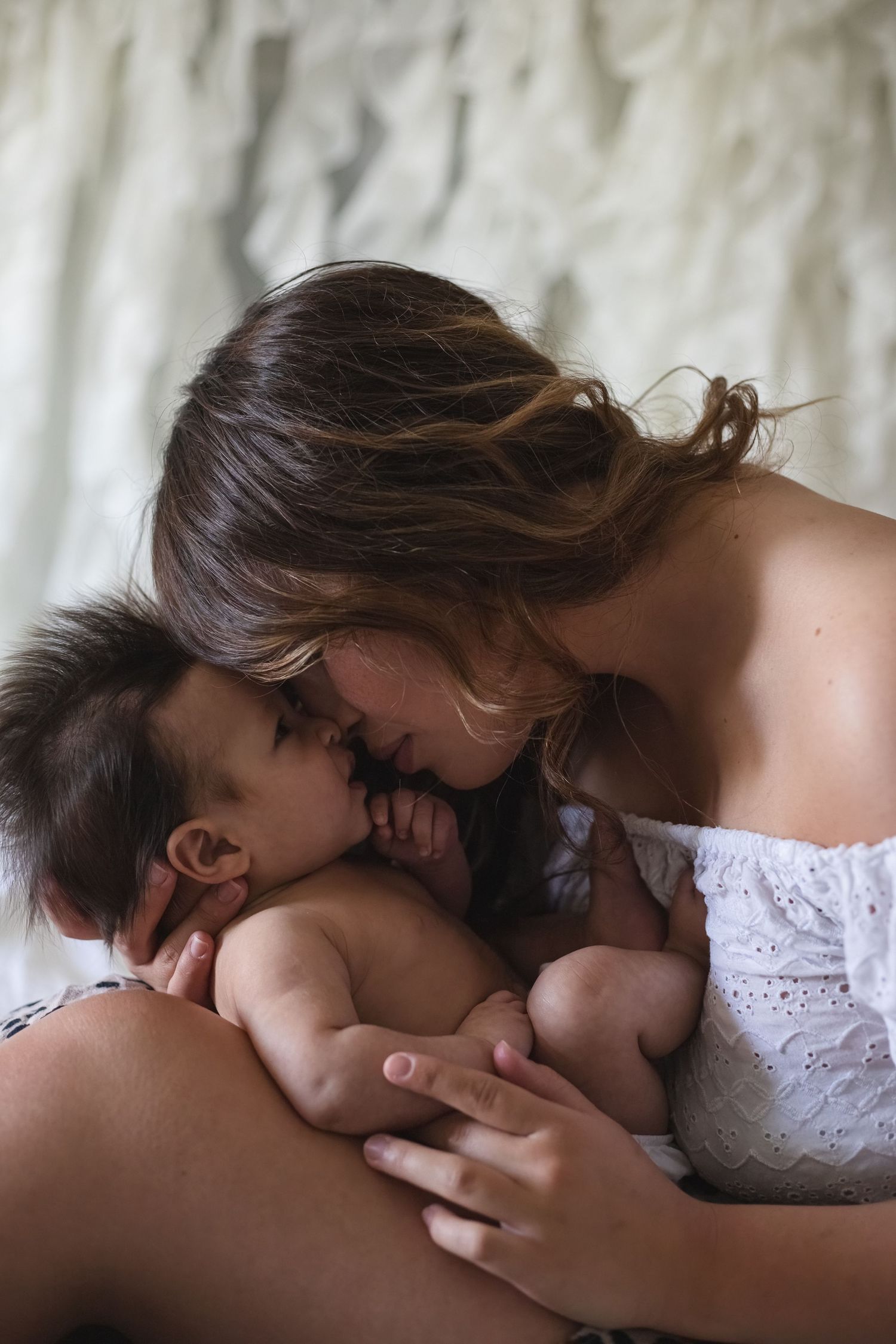 A tender moment between a parent and baby as they share loving nose kisses while lying down.