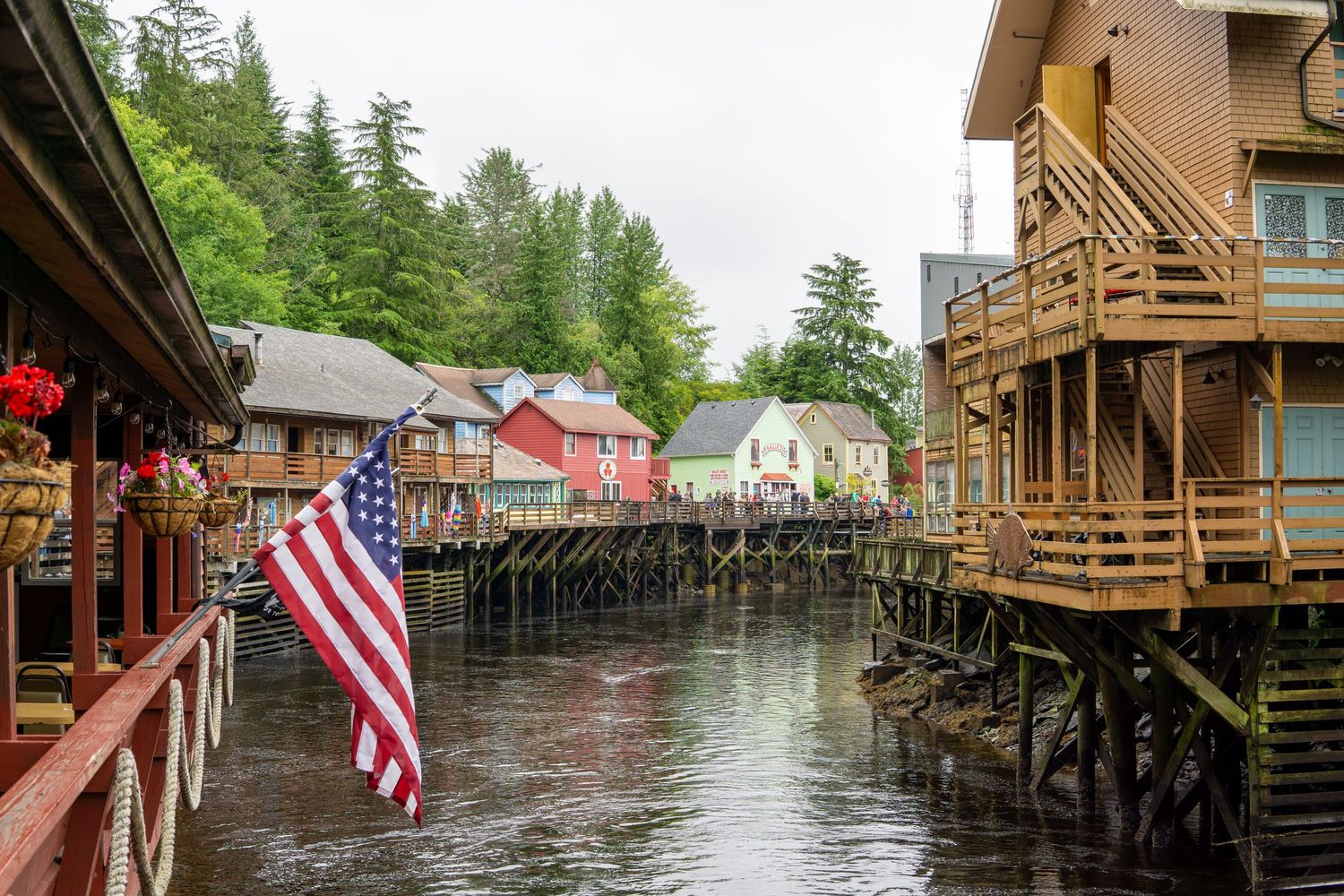 Historic waterfront buildings on stilts with American flag in Ketchikan's Creek Street.