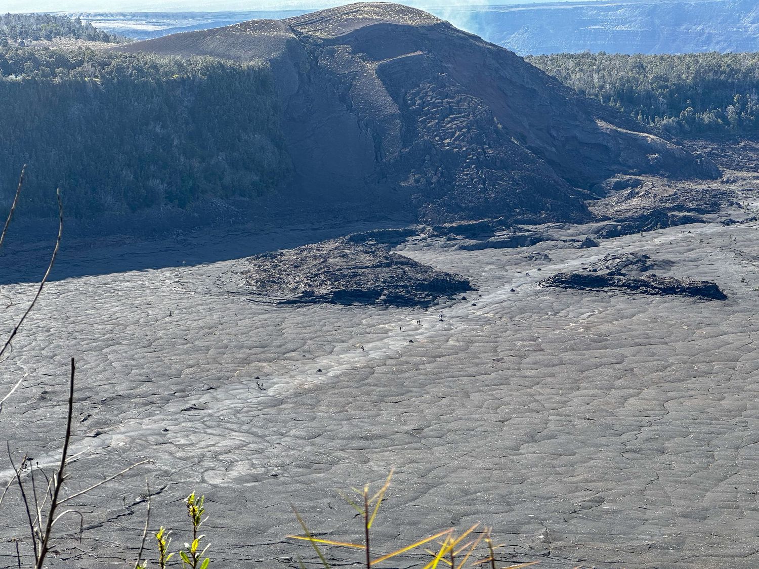 Volcanic landscape with hardened lava flow and mountainous terrain at Kilauea Volcano in Hawaii.