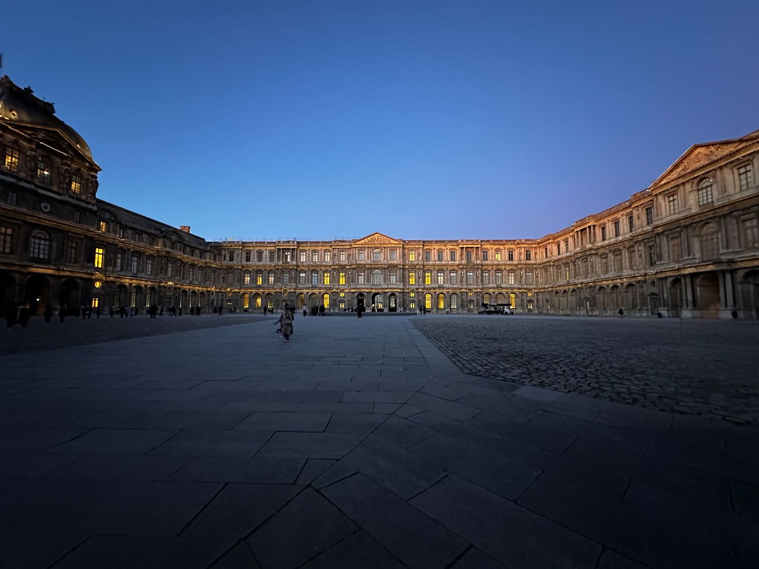 Historic palace courtyard illuminated at dusk with golden light reflecting off ornate stone architecture.