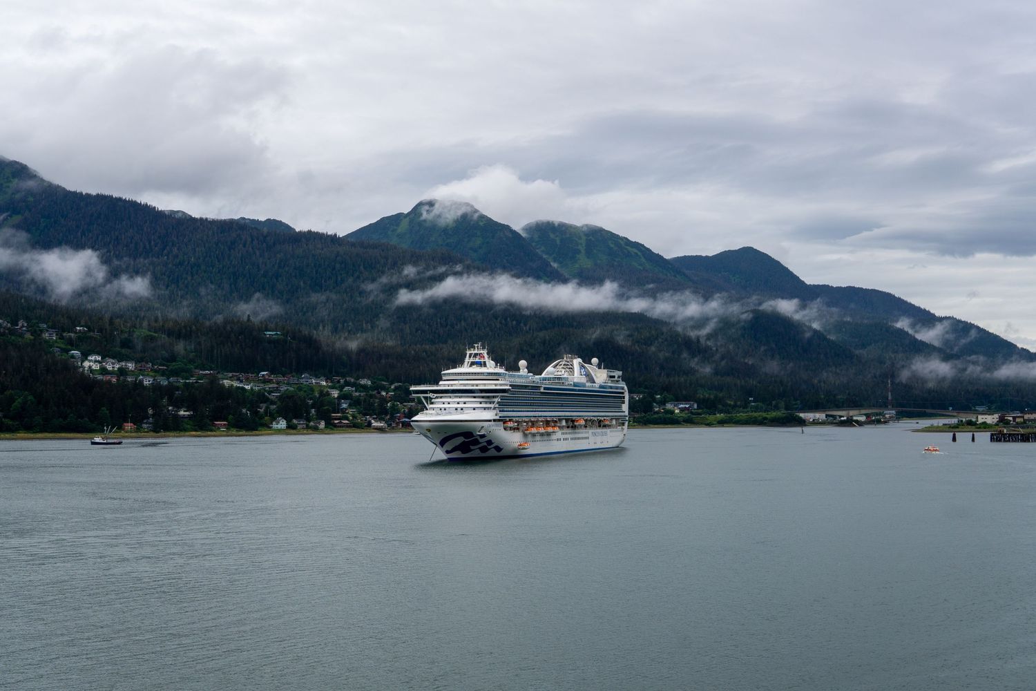Cruise ship floating in calm waters with foggy mountains behind.