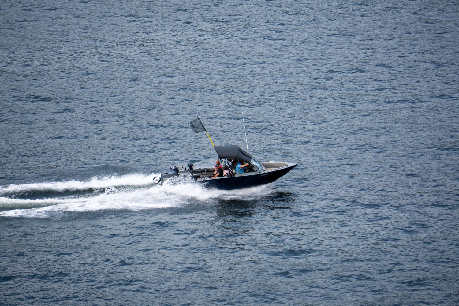 Small fishing boat racing across Vancouver Harbour creating wake.