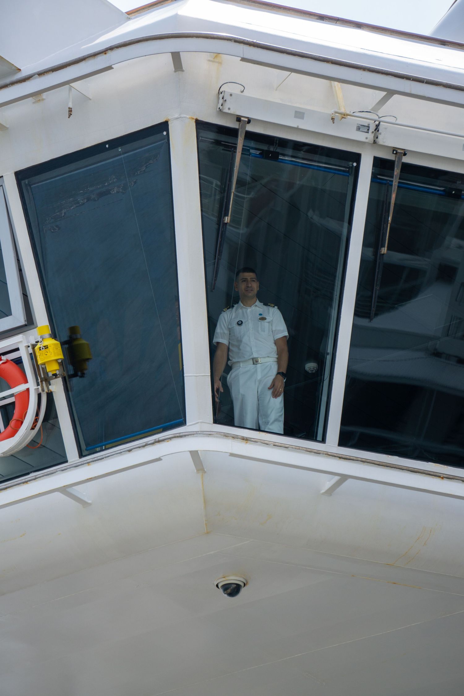 Ship captain standing in white uniform inside vessel control room.