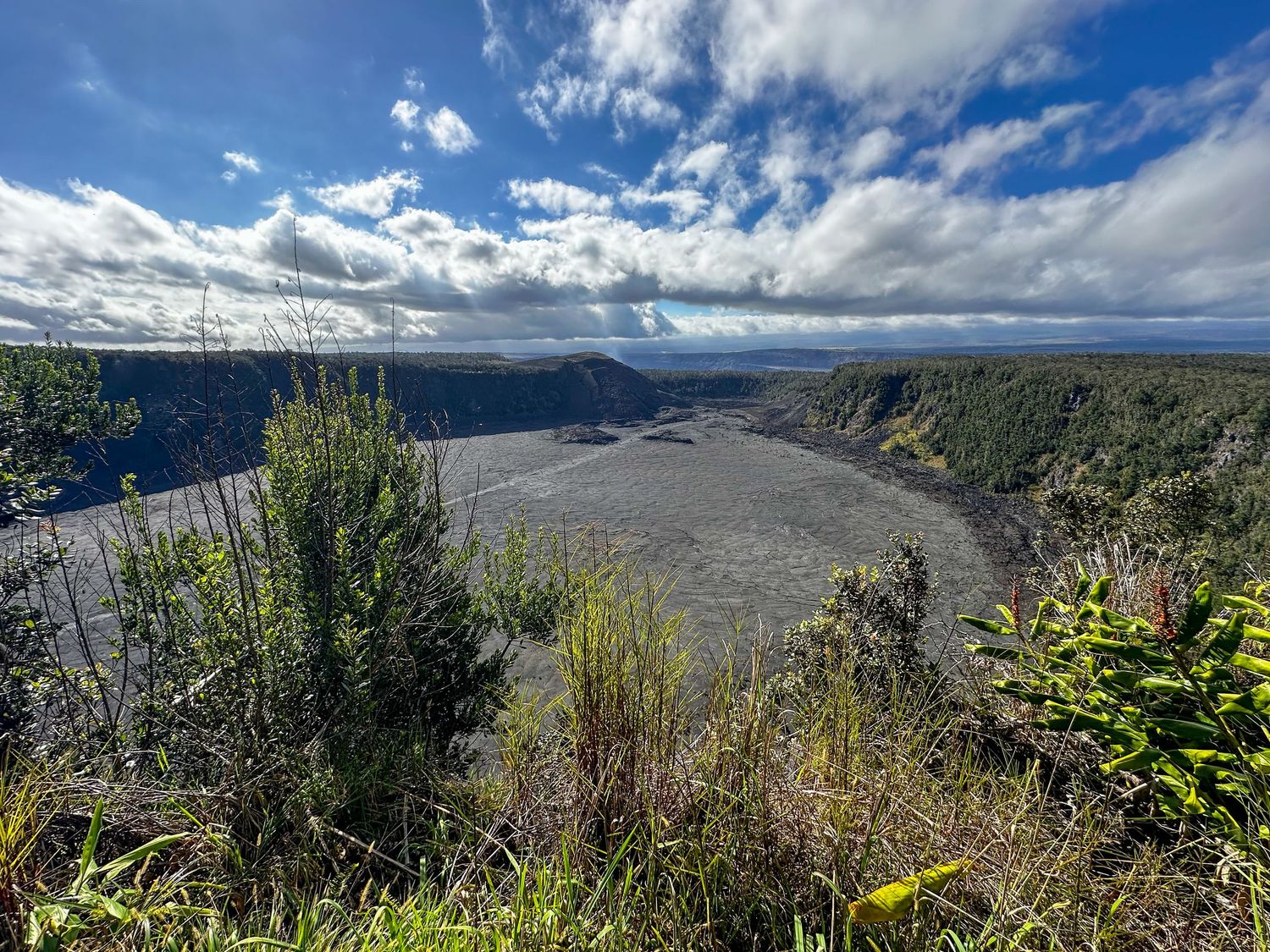 Scenic overlook of a winding river valley with dramatic clouds and lush green vegetation in Hawaii Volcanoes National Park.