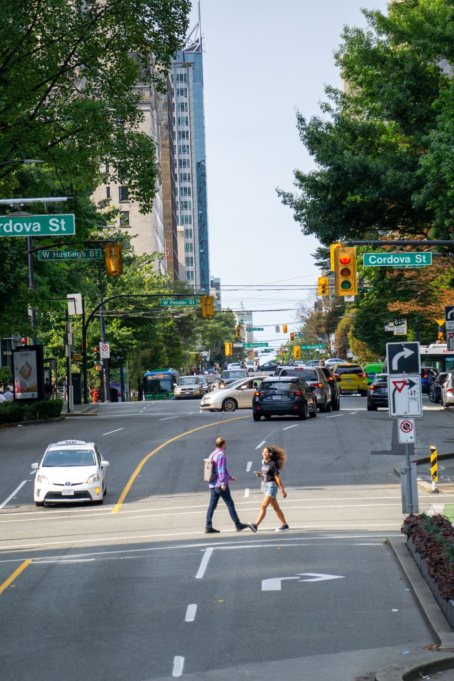 Busy urban intersection at Cordova Street with pedestrians crossing and tall buildings.