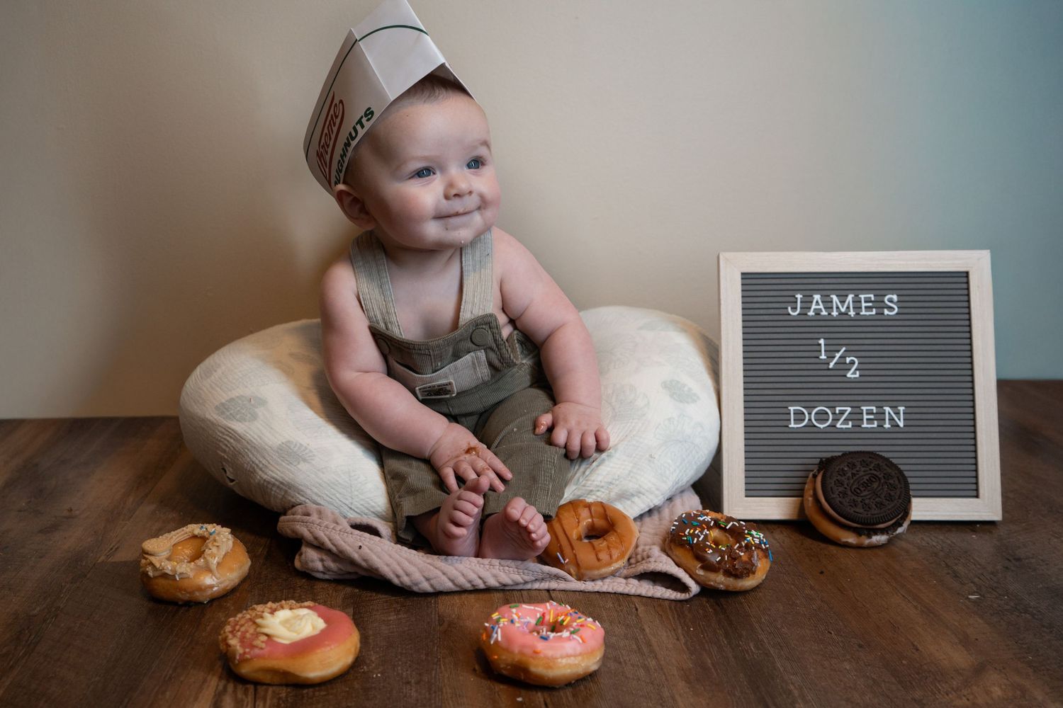 Baby James sits among donuts celebrating his half dozen (6 month) birthday milestone with a letter board sign.