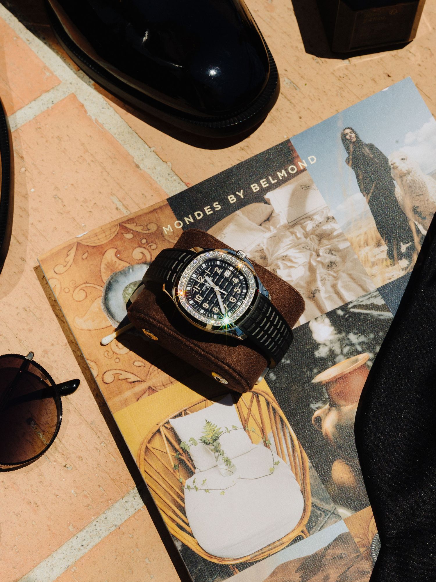 Grooms wedding accessories flat lay featuring luxury watch, sunglasses, black shoes on Belmond magazine.