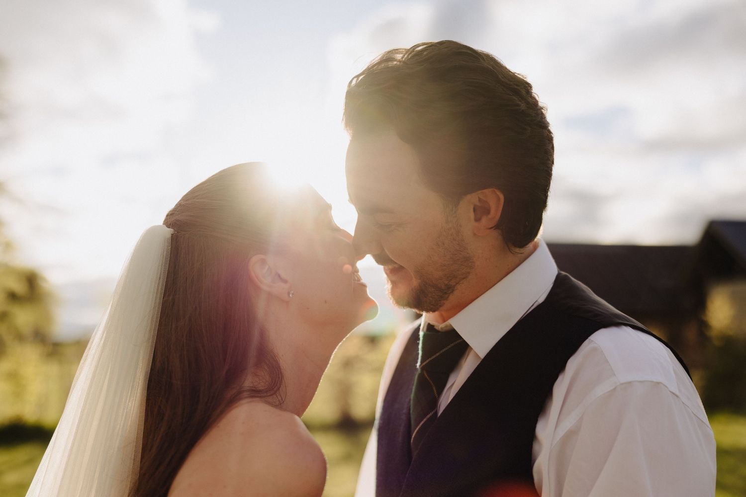 Bride and groom sharing a romantic moment outdoors with golden sunlight glowing between them on their wedding day.