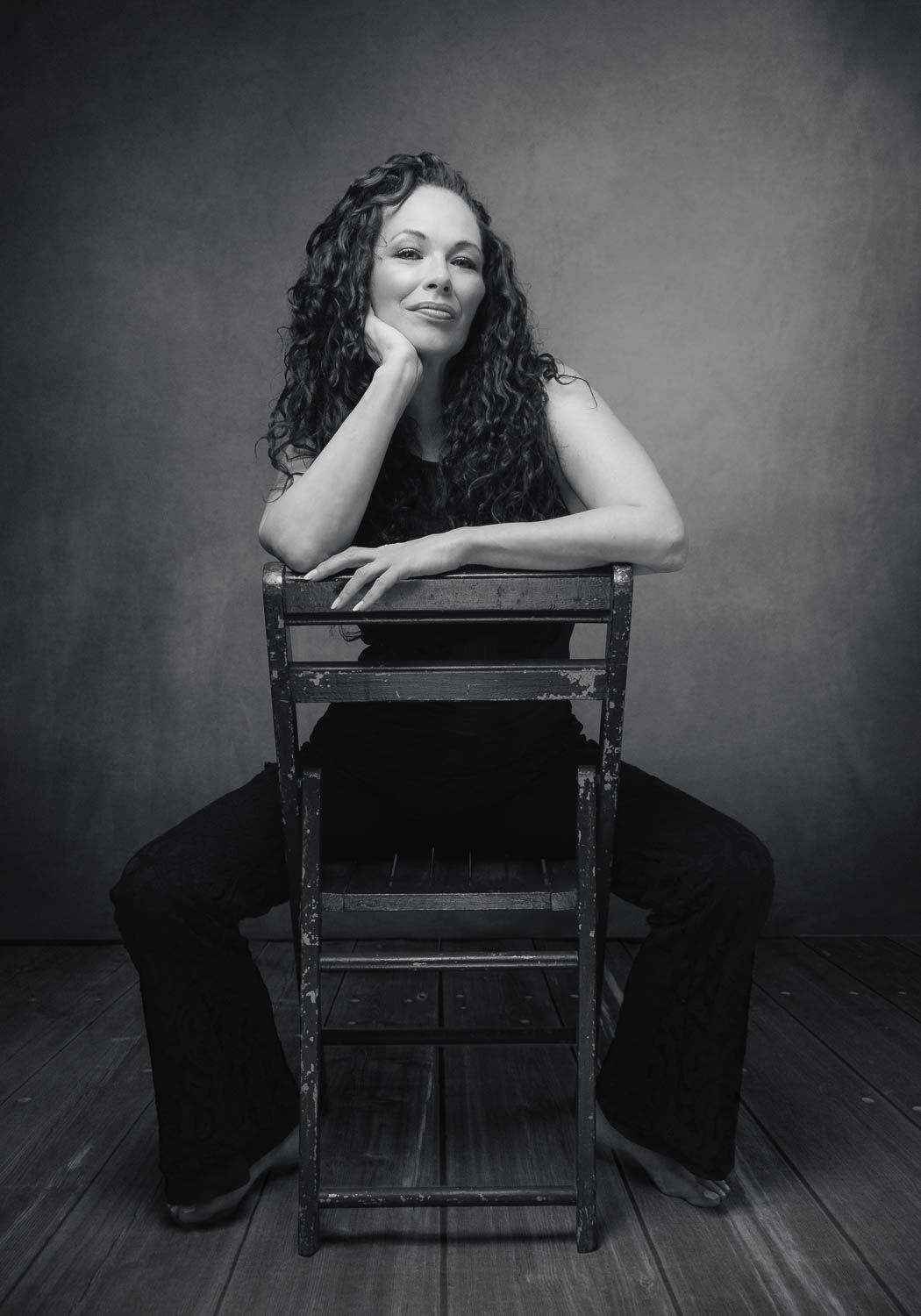Creative portrait of woman with dark hair sitting on a wooden chair