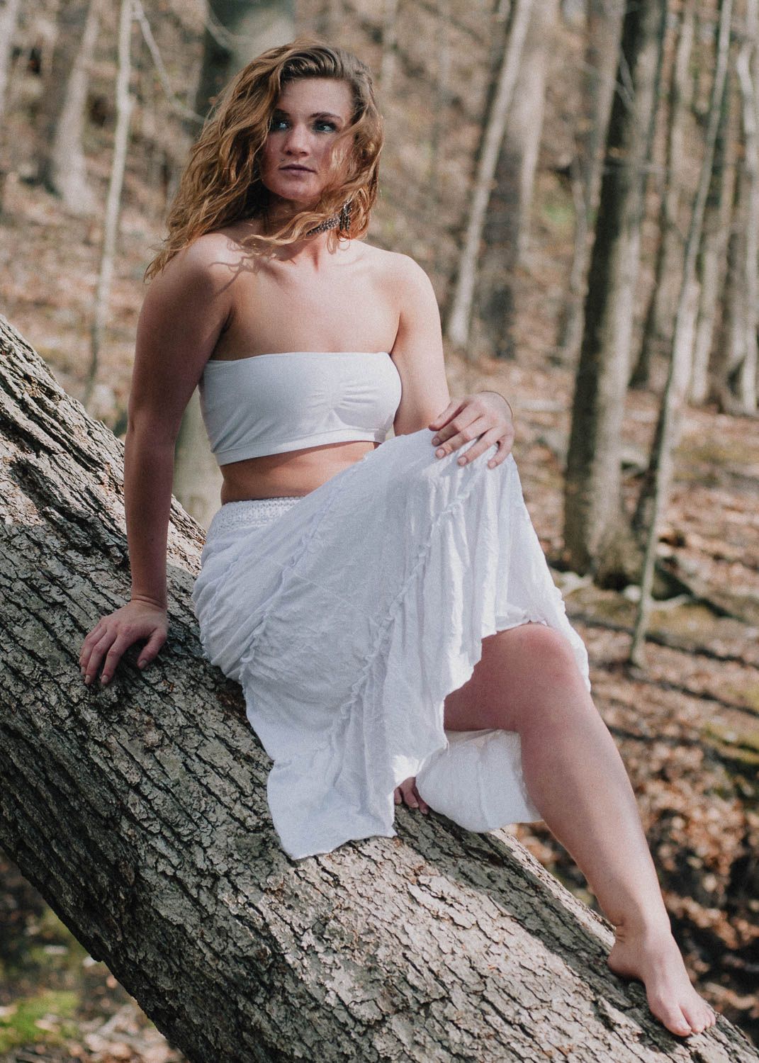 Lifestyle photo of a young woman outside sitting on a tree