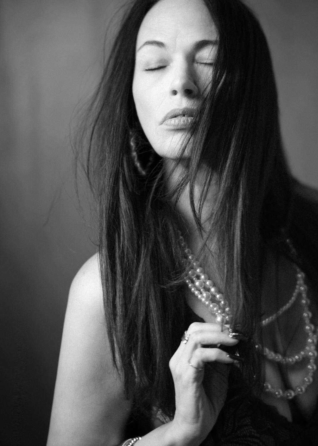 Creative and moody black and white portrait of young woman with dark hair in studio