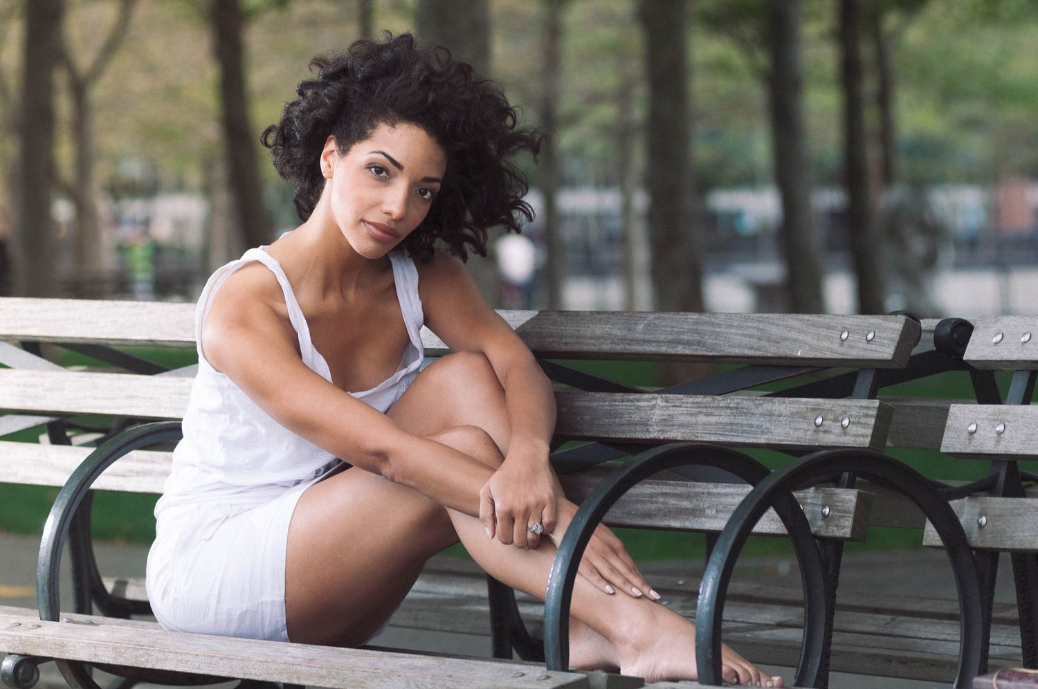 Lifestyle photo of a young woman outside sitting on a park bench