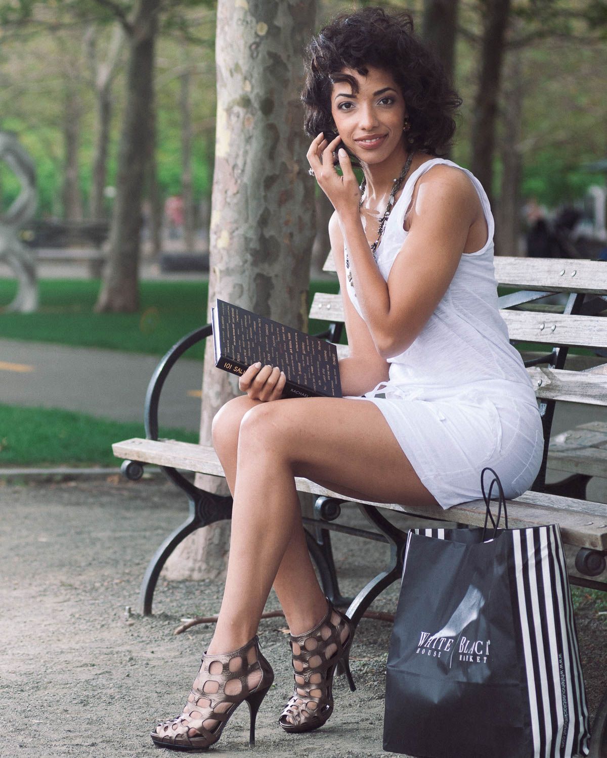 Fashion branding photo for clothing with a young woman outside sitting on a park bench