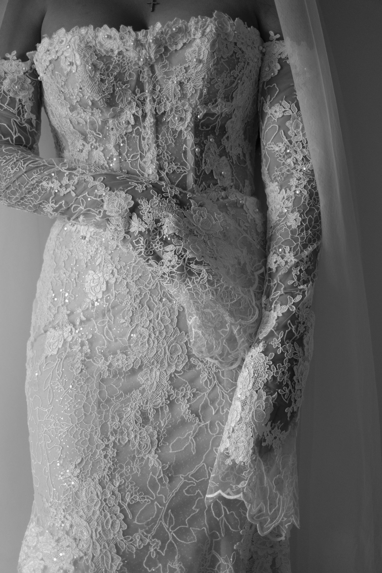 Close-up of a bride in an elegant lace wedding gown with long lace gloves, captured in black and white.
