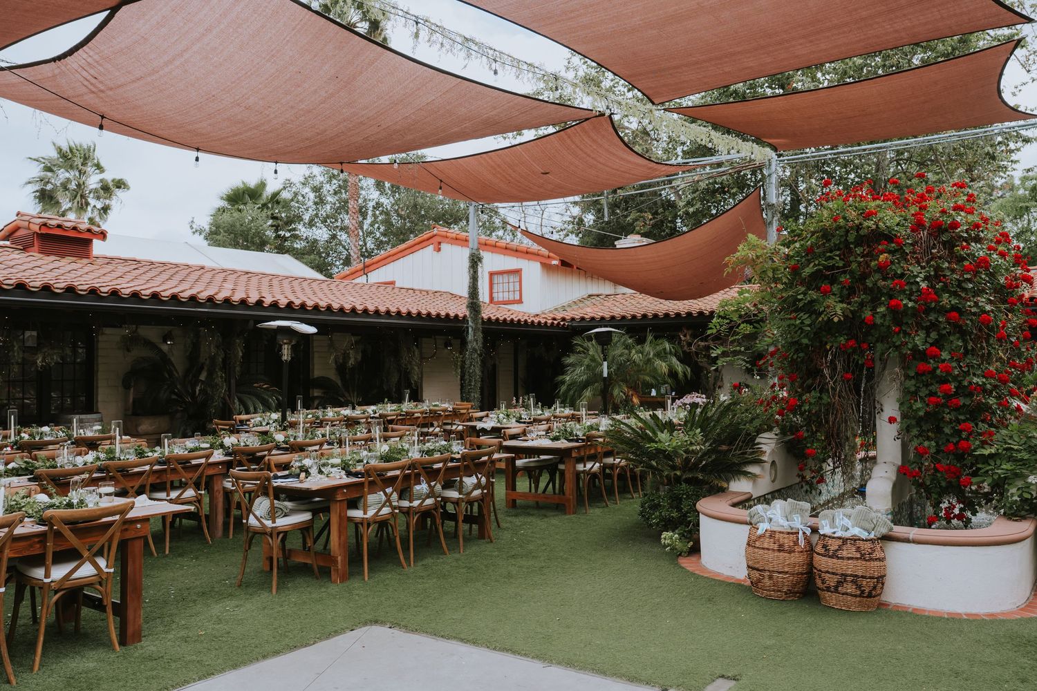 Spanish-style outdoor wedding venue with rustic tables and orange shade sails.