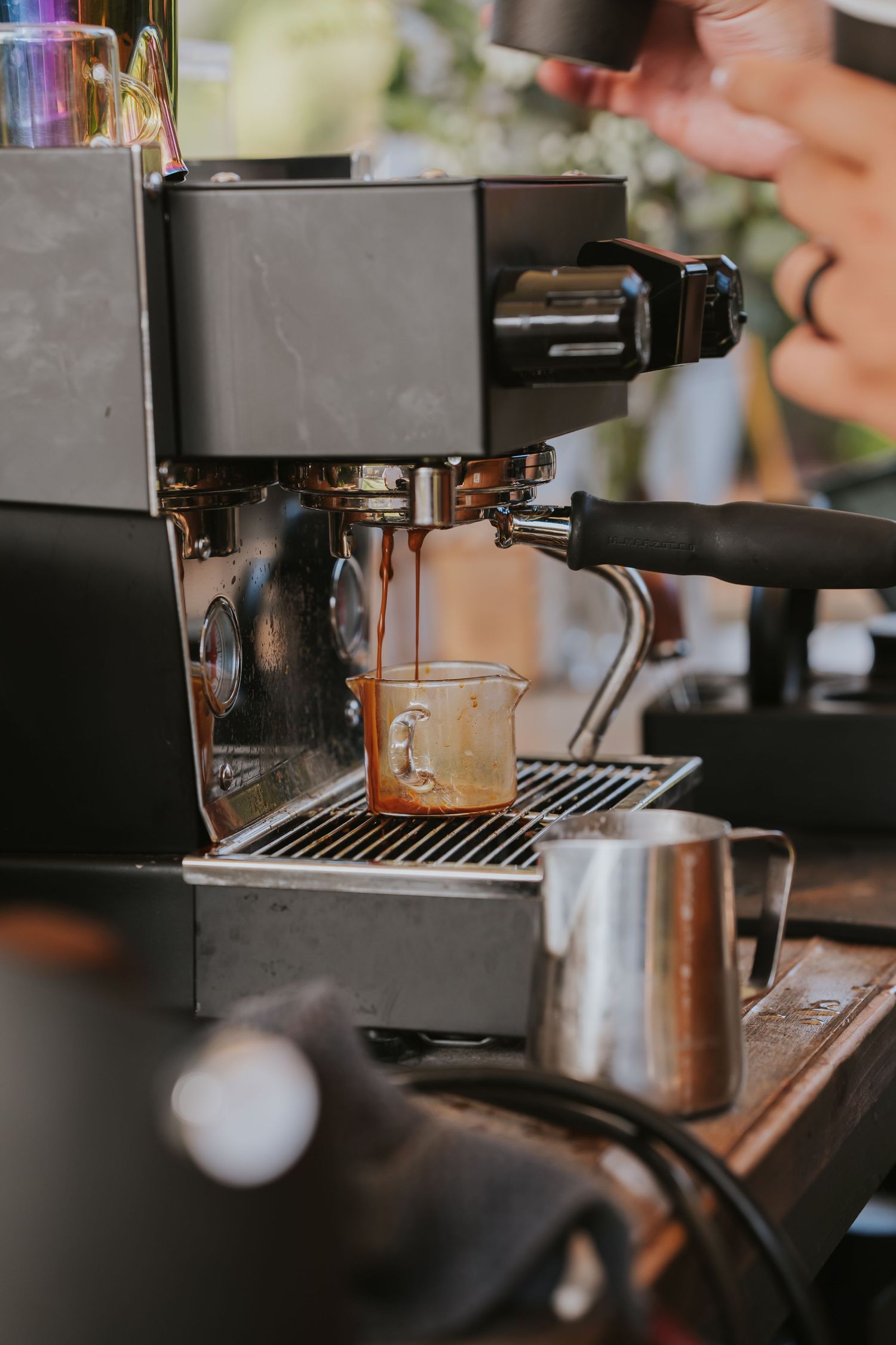 Close-up sequence of espresso being brewed from a professional coffee machine into a glass cup.