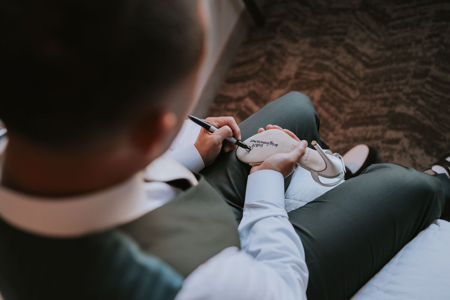 A person wearing formal wedding attire sits in a dimly lit room preparing for a ceremony.