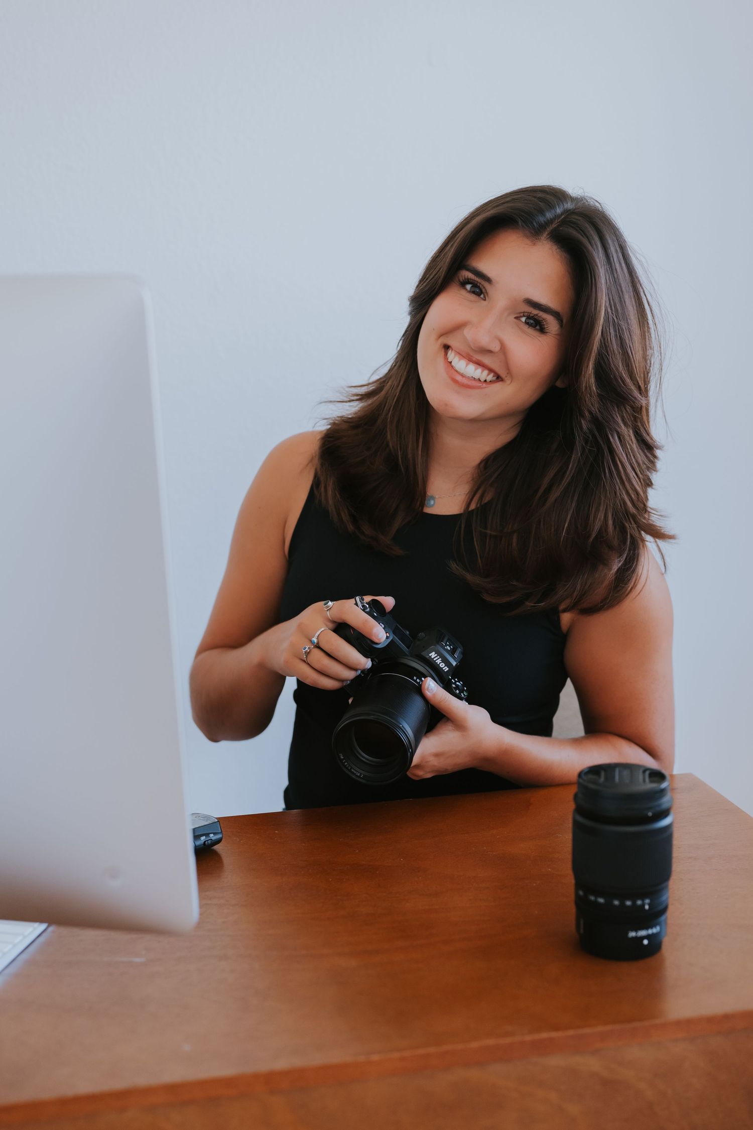 Person with camera equipment leaning on wooden desk during photo session.