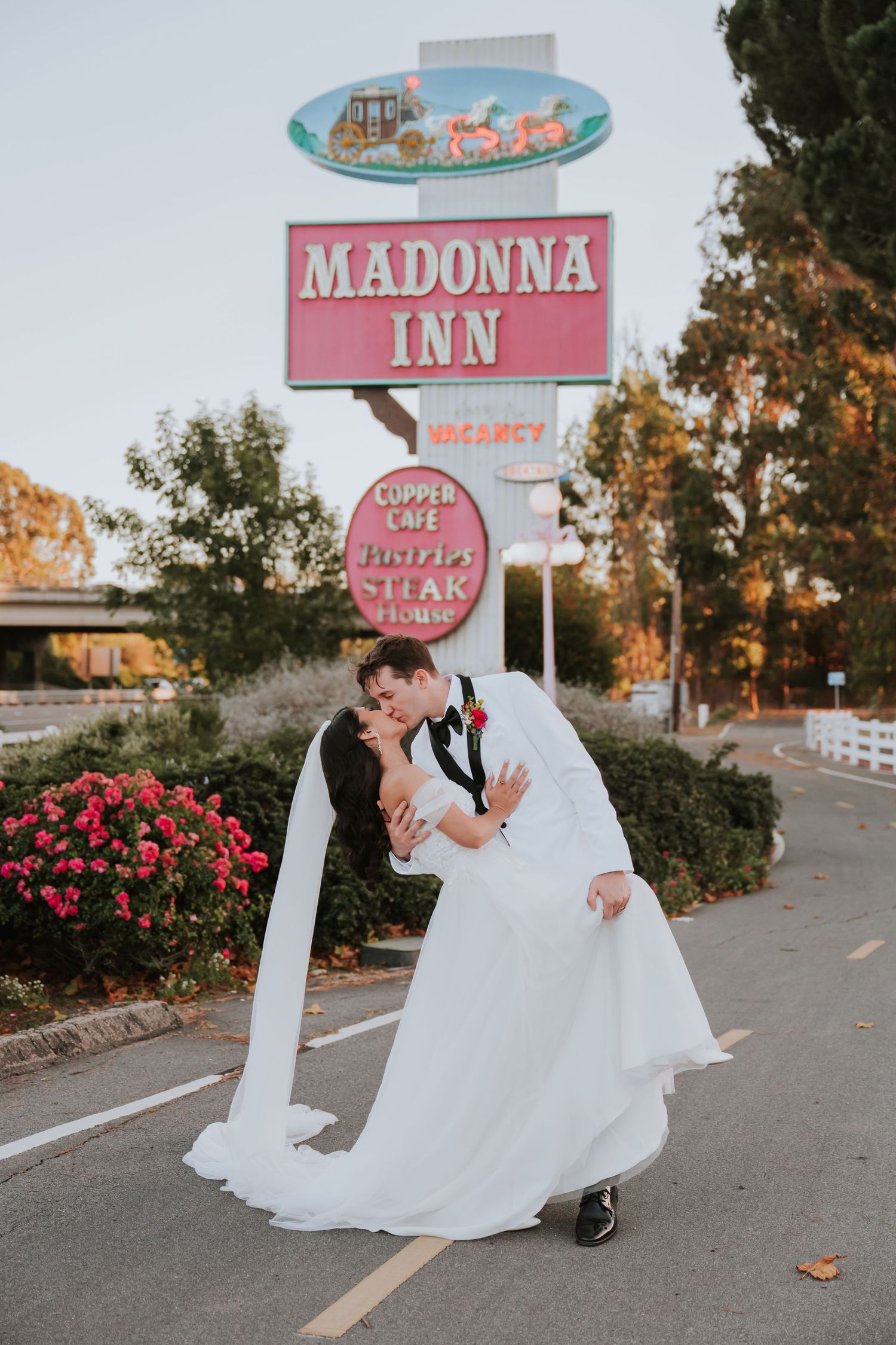 Romantic wedding portraits captured at the retro Madonna Inn with pink neon signage.
