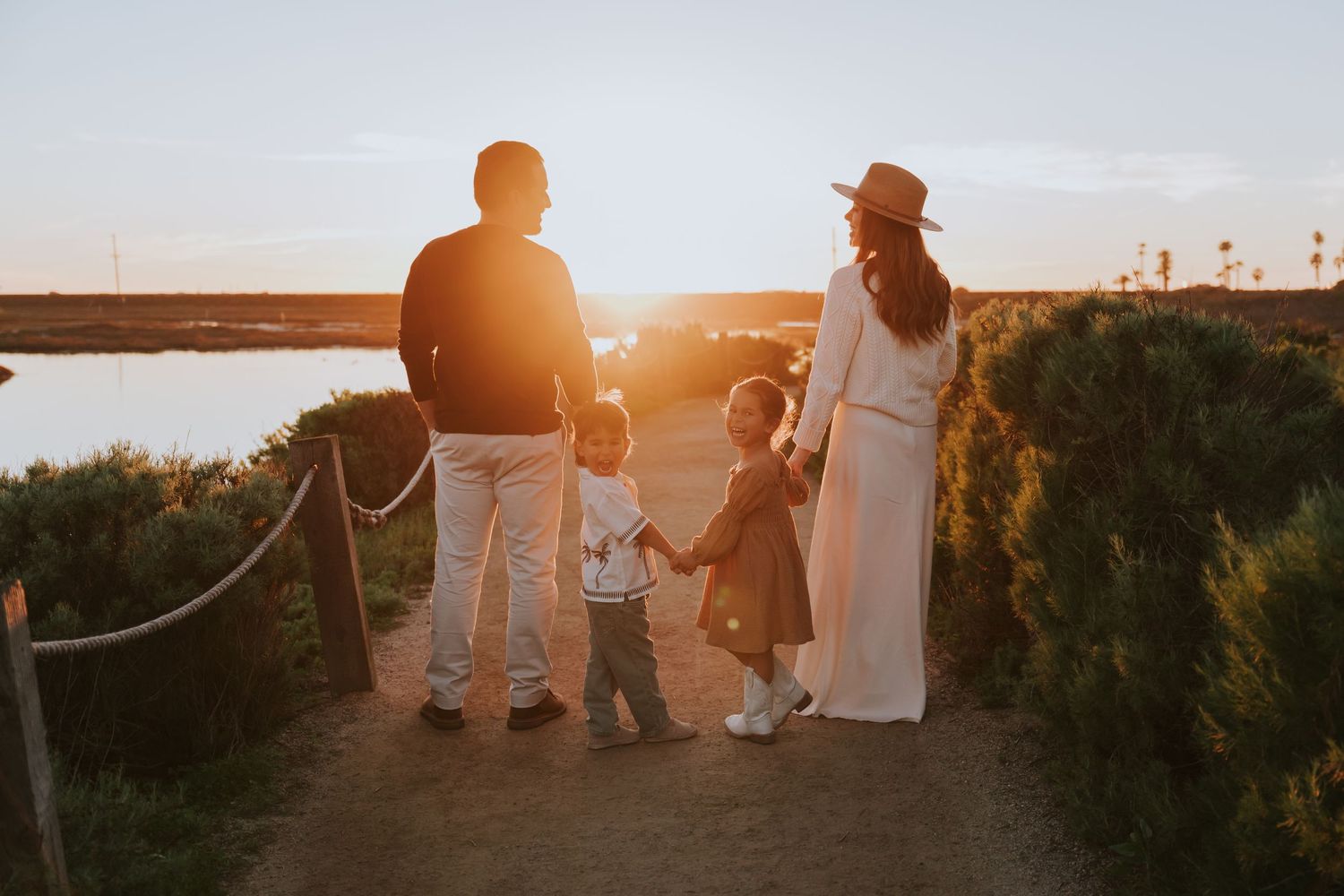 Silhouettes of wedding party against a golden sunset on a coastal path.