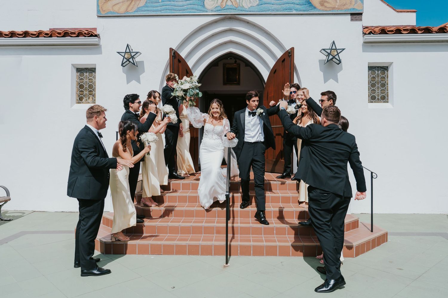 Wedding guests gathered on white church steps creating a festive atmosphere.