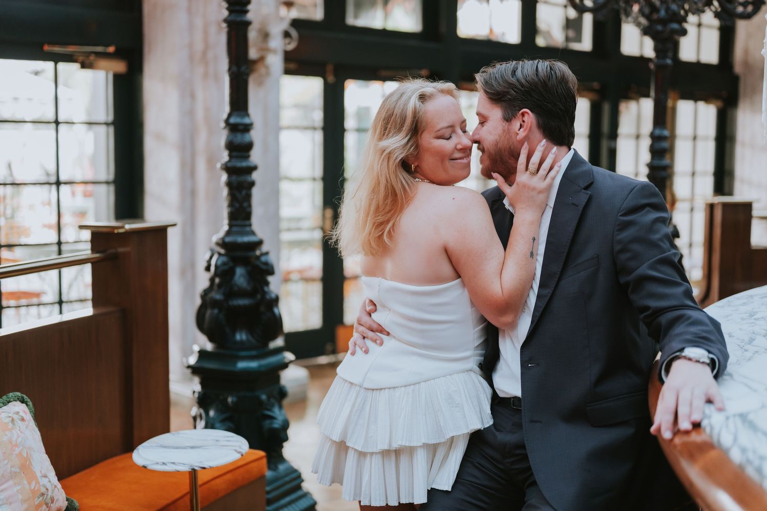 Couple sharing a romantic moment in an elegant indoor venue, woman in white dress and man in dark suit.