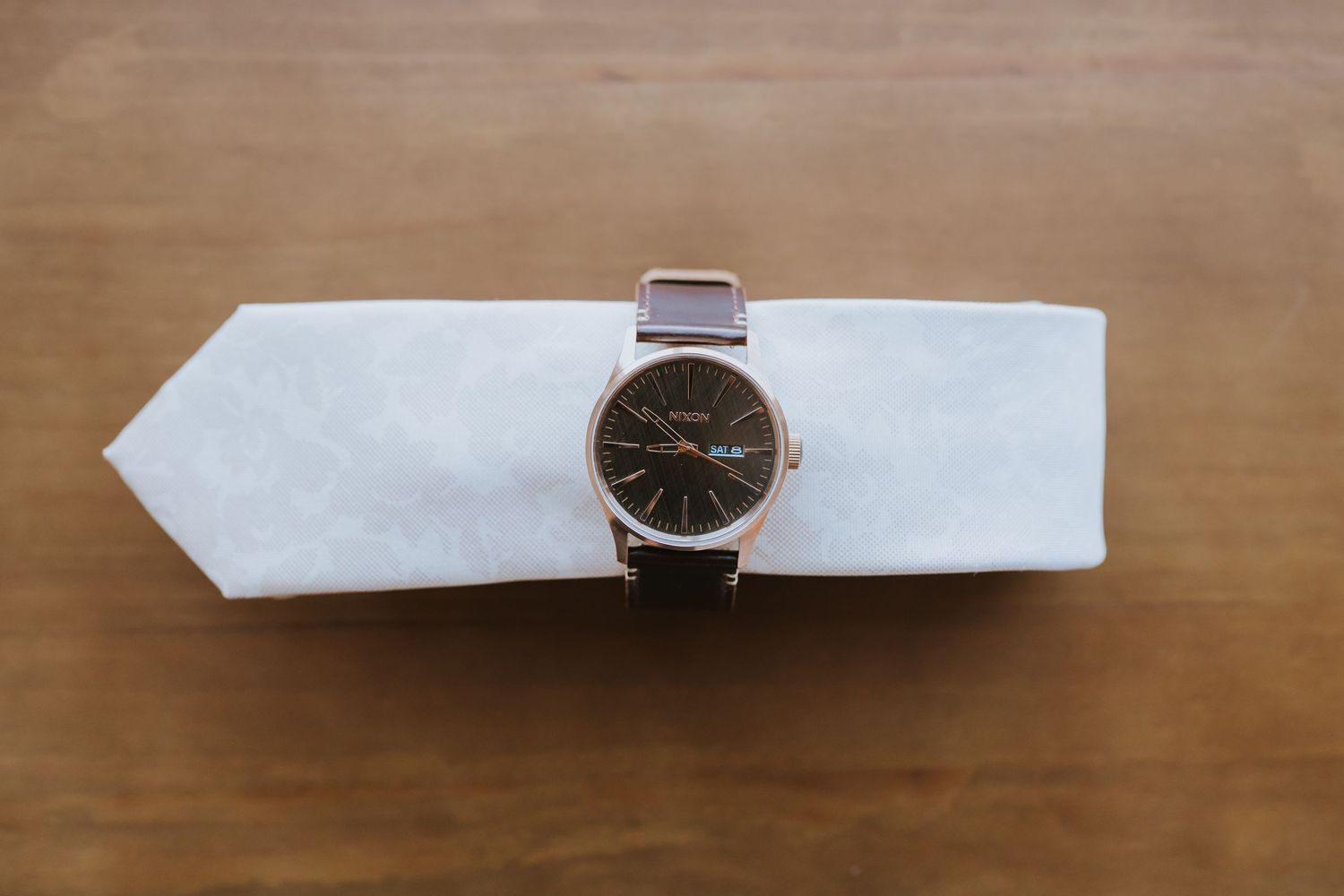 Multiple minimalist wristwatches with leather straps displayed on a wooden surface.