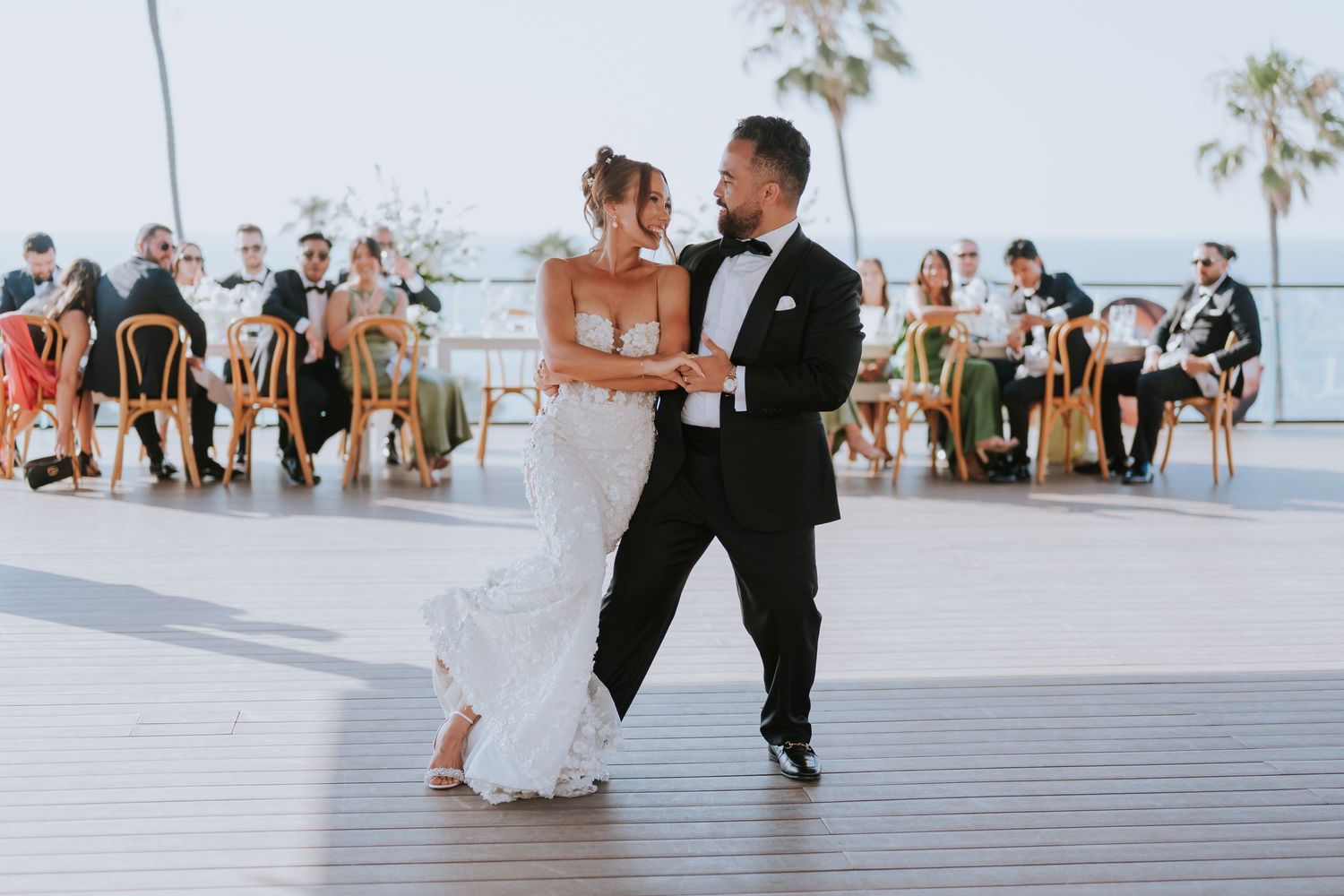 Couple dancing on an oceanfront terrace during their wedding celebration.